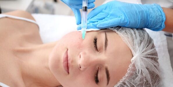 Un cosmétologue effectue une procédure de rajeunissement de la peau du visage avec du plasma